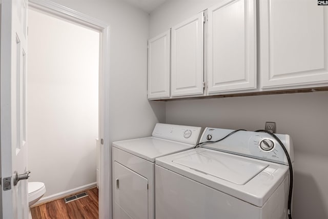 laundry area with cabinets, washer and dryer, and dark hardwood / wood-style floors