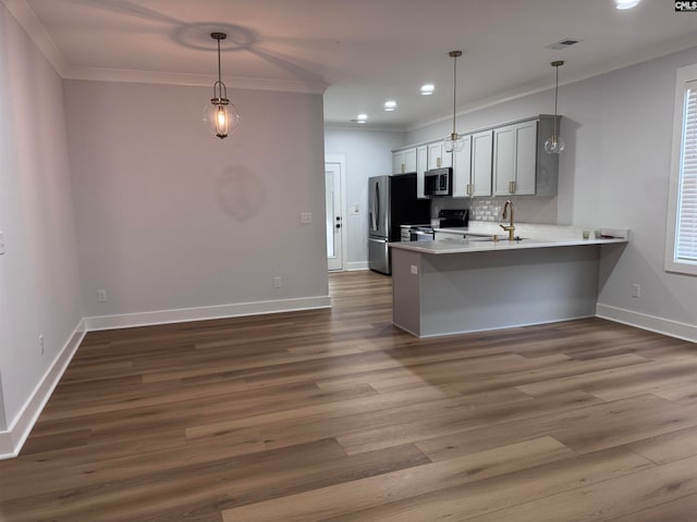 kitchen featuring crown molding, decorative backsplash, appliances with stainless steel finishes, decorative light fixtures, and kitchen peninsula