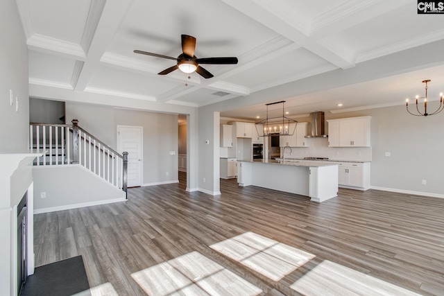 unfurnished living room featuring wood finished floors, baseboards, and stairs