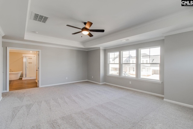 spare room featuring a raised ceiling, visible vents, and baseboards