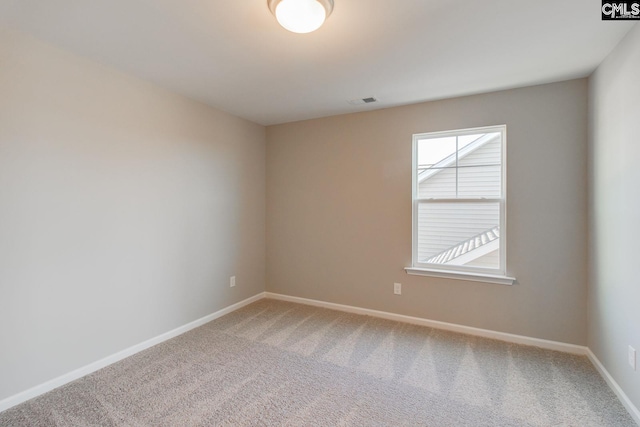 empty room featuring carpet floors, visible vents, and baseboards