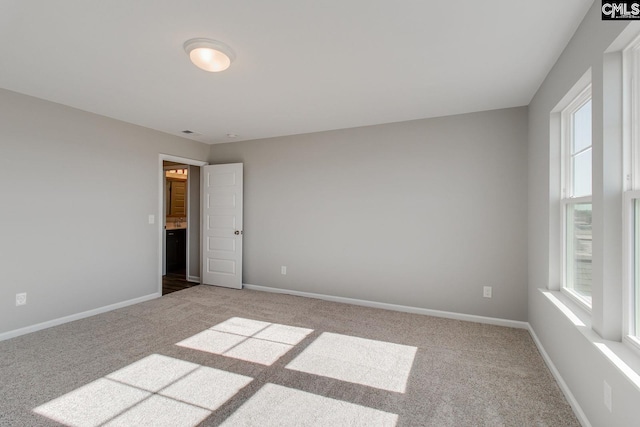 carpeted empty room featuring baseboards and a wealth of natural light