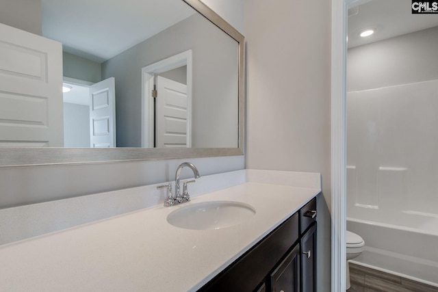 full bathroom with wood finished floors, vanity, and toilet