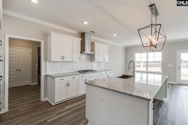 kitchen featuring dark wood-style flooring, a sink, ornamental molding, wall chimney exhaust hood, and stainless steel gas stovetop