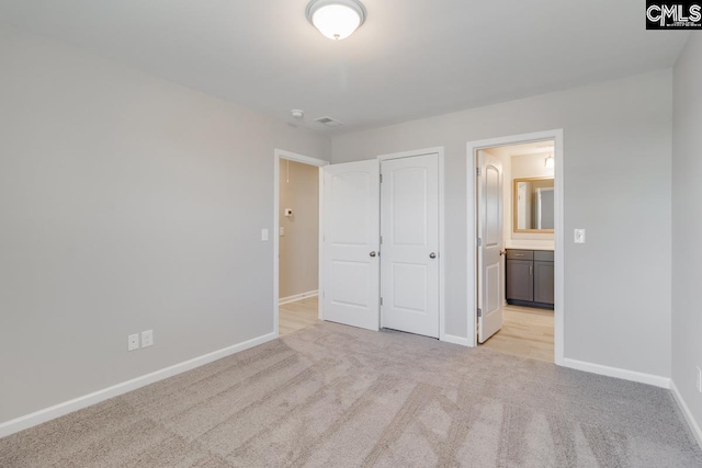 unfurnished bedroom with light colored carpet, connected bathroom, visible vents, and baseboards