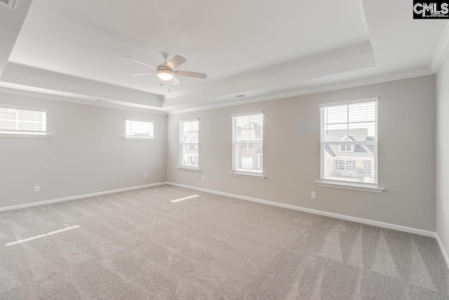 unfurnished room with ornamental molding, a tray ceiling, light colored carpet, and baseboards