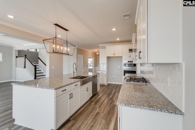 kitchen with visible vents, white cabinets, wood finished floors, stainless steel appliances, and a sink