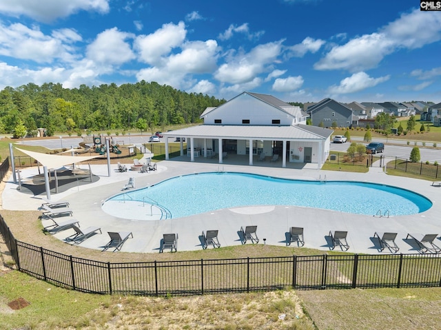 community pool with a patio area, fence, and a yard