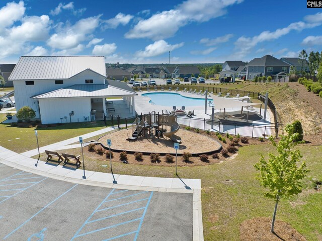 surrounding community featuring uncovered parking, playground community, fence, and a residential view