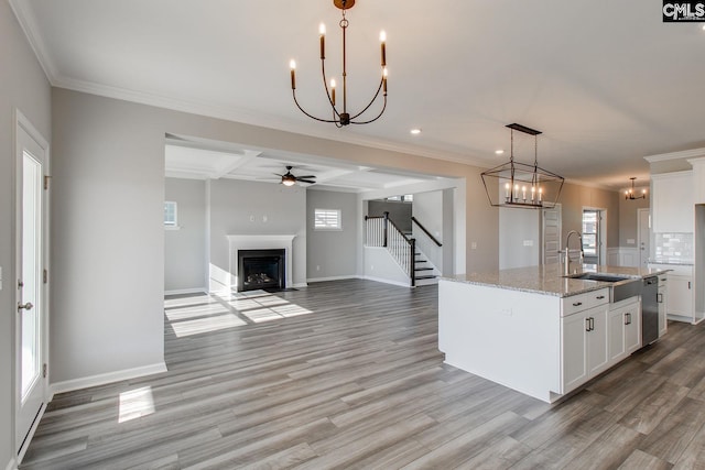 kitchen featuring a fireplace with flush hearth, white cabinetry, a sink, and light wood finished floors