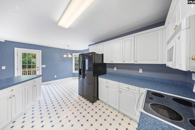 kitchen with black fridge, a chandelier, decorative light fixtures, and white cabinets