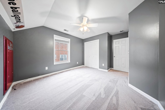 unfurnished bedroom with ceiling fan, light carpet, a closet, and lofted ceiling