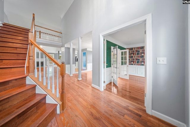 staircase featuring ornate columns, hardwood / wood-style flooring, and crown molding