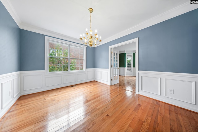 empty room featuring light wood-type flooring, a chandelier, and ornamental molding