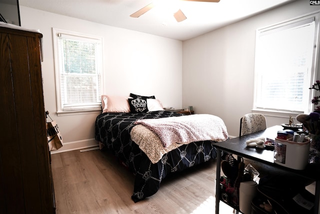 bedroom featuring hardwood / wood-style flooring, ceiling fan, and multiple windows