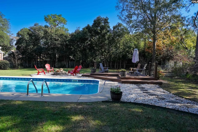 view of pool with a wooden deck, a fire pit, and a lawn