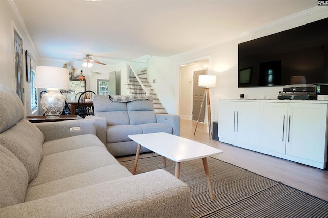 living area with a ceiling fan, light wood-style flooring, stairs, and ornamental molding