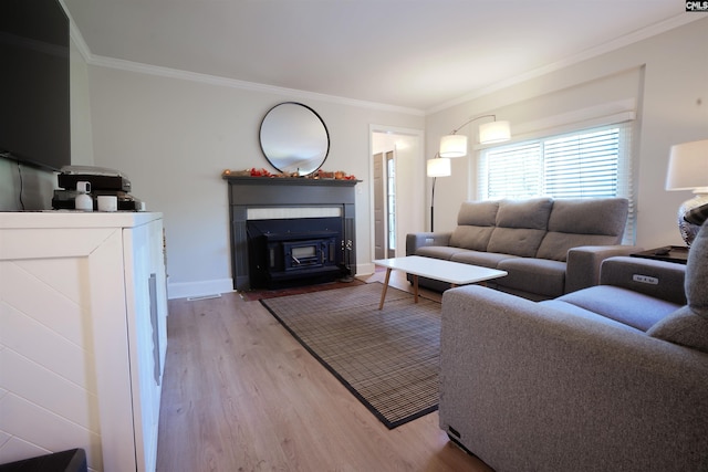 living room featuring washer / clothes dryer, a wood stove, crown molding, and light hardwood / wood-style flooring