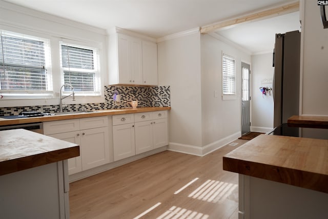 kitchen featuring crown molding, light wood-type flooring, backsplash, and butcher block counters