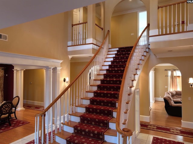 stairs with a high ceiling, ornamental molding, and hardwood / wood-style flooring