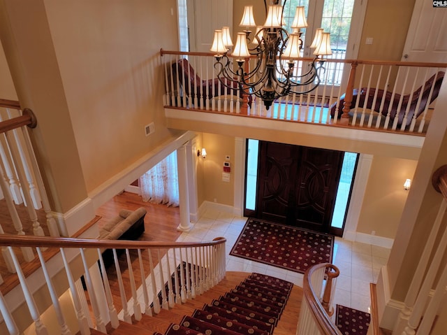 tiled entryway with a towering ceiling and an inviting chandelier