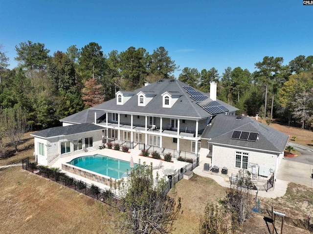 rear view of house featuring a patio area, solar panels, and a balcony