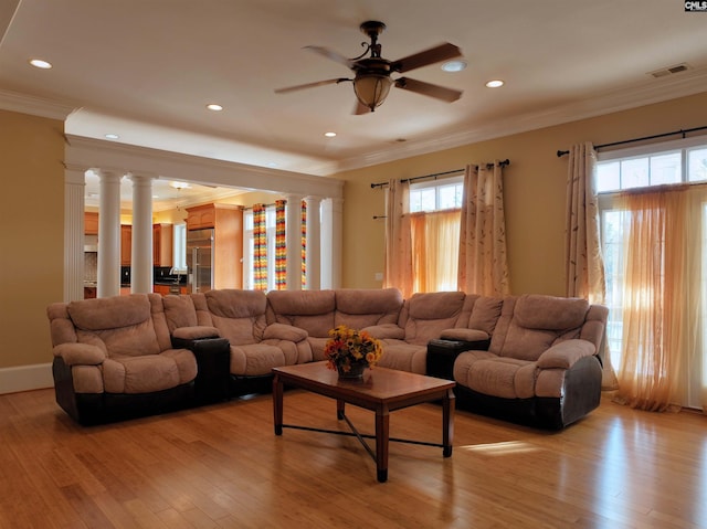 living room featuring light hardwood / wood-style flooring, a healthy amount of sunlight, and decorative columns