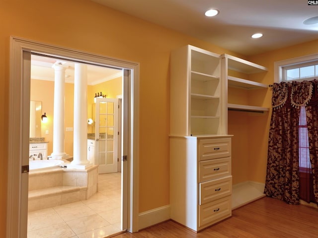 spacious closet with decorative columns and light hardwood / wood-style flooring