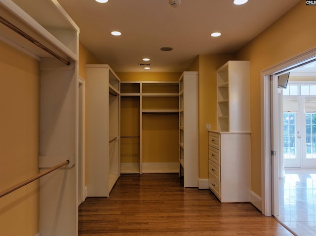 walk in closet with french doors and wood-type flooring