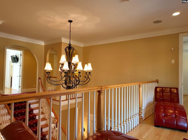 hall featuring wood-type flooring, crown molding, and a notable chandelier