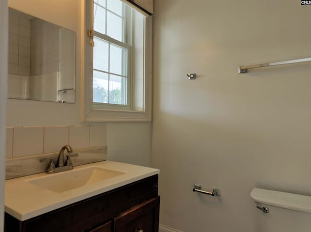 bathroom with toilet, vanity, and decorative backsplash