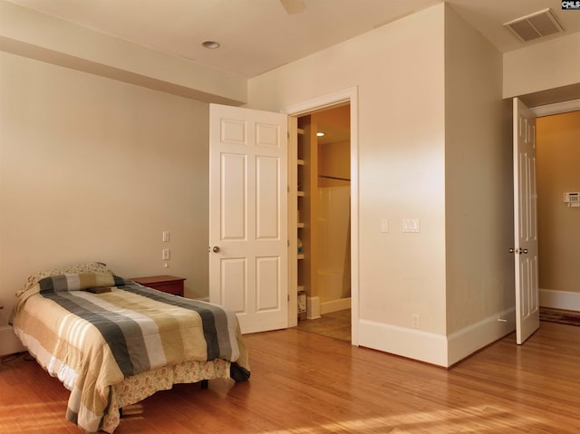 bedroom with a spacious closet and hardwood / wood-style flooring