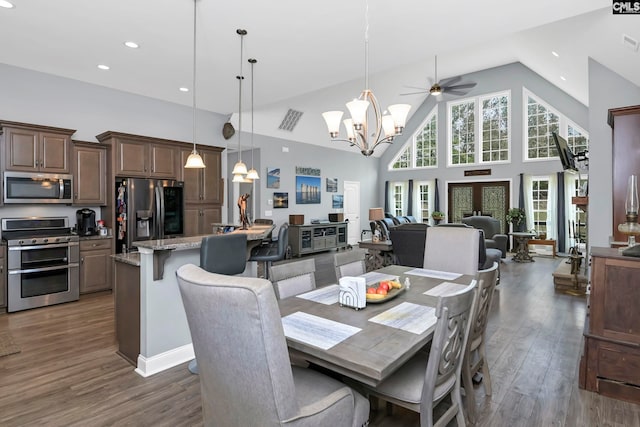 dining room featuring dark wood-type flooring, ceiling fan with notable chandelier, and high vaulted ceiling