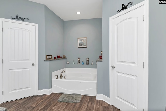 bathroom with wood-type flooring and a bath