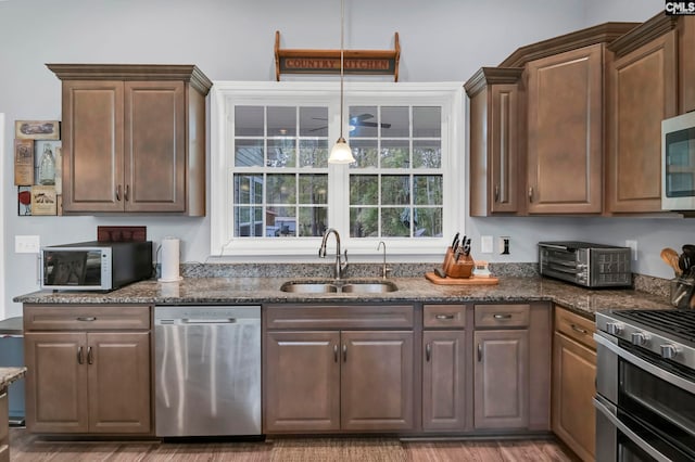 kitchen featuring stainless steel appliances, wood-type flooring, sink, and dark stone counters