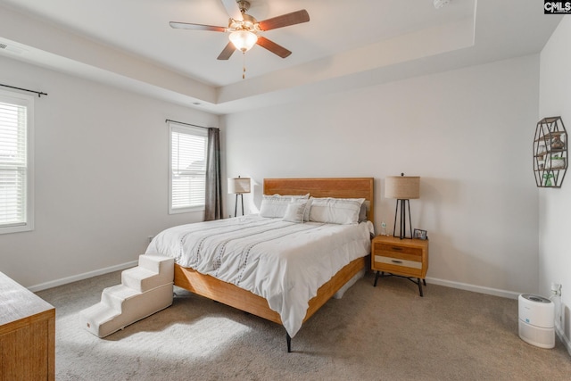 carpeted bedroom featuring ceiling fan and a tray ceiling