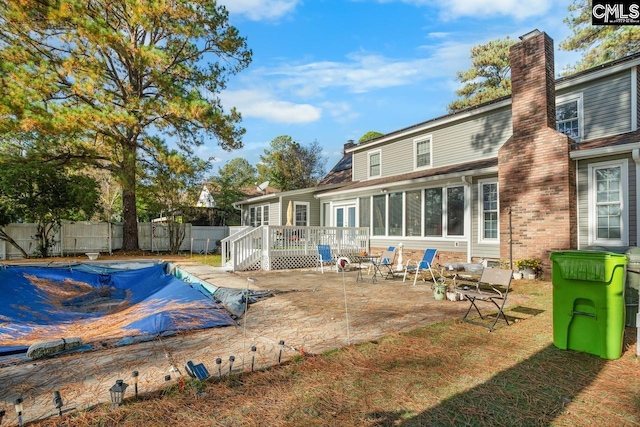 rear view of house featuring a covered pool and a patio area