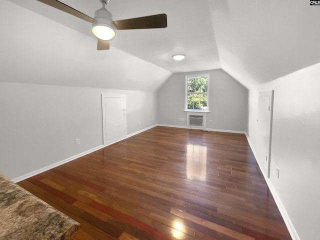 additional living space with a wall mounted AC, dark hardwood / wood-style flooring, ceiling fan, and vaulted ceiling