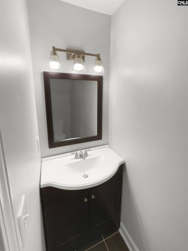 bathroom with toilet, vanity, and tile patterned floors