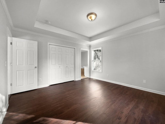 unfurnished bedroom with dark wood-type flooring, crown molding, and a raised ceiling