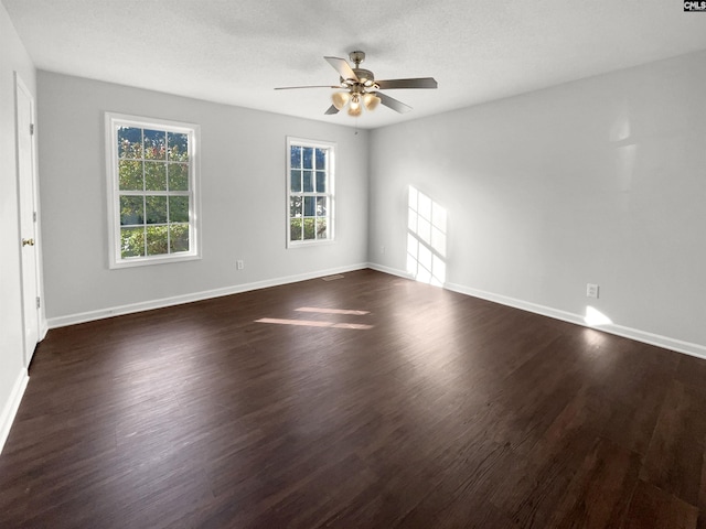 spare room featuring a textured ceiling, dark wood-type flooring, and a healthy amount of sunlight