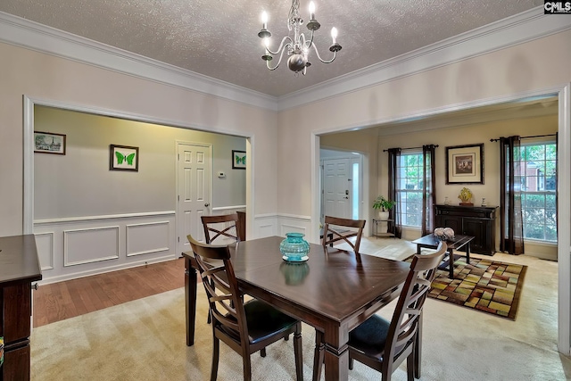 dining space featuring a chandelier, a textured ceiling, light wood-type flooring, and ornamental molding