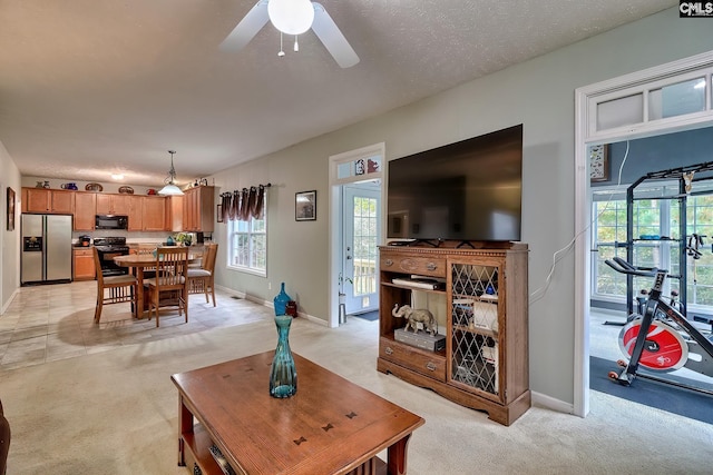 carpeted living room with ceiling fan and a textured ceiling