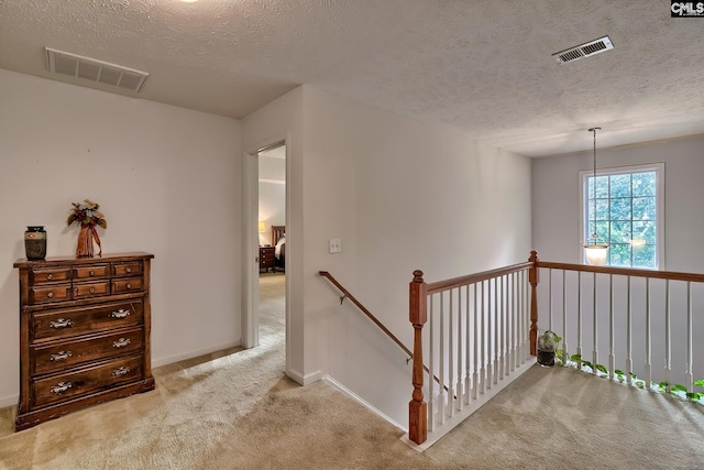 corridor with a textured ceiling and light colored carpet