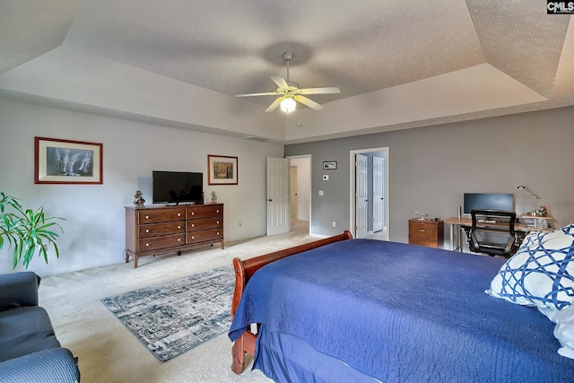 bedroom with a tray ceiling, light colored carpet, and ceiling fan