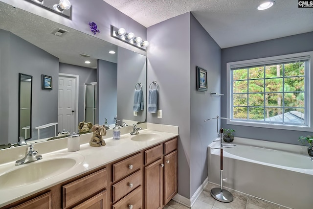 bathroom featuring plus walk in shower, vanity, a textured ceiling, and tile patterned floors