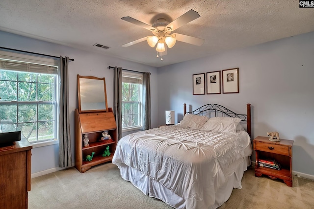 carpeted bedroom featuring multiple windows, a textured ceiling, and ceiling fan