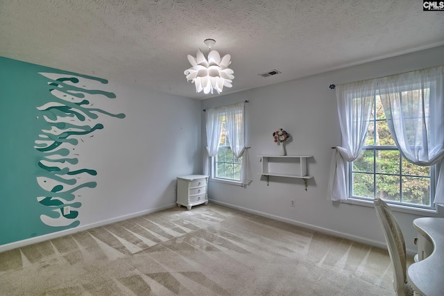 unfurnished room featuring a textured ceiling, light carpet, and an inviting chandelier