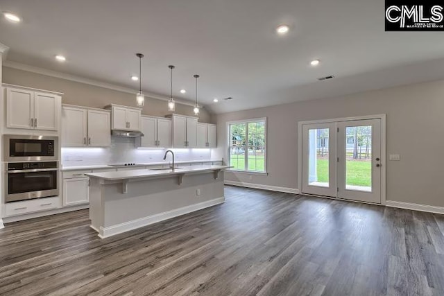 kitchen with built in microwave, white cabinetry, stainless steel oven, and hanging light fixtures