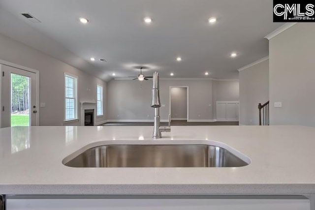 kitchen featuring ceiling fan, light stone countertops, sink, and a wealth of natural light